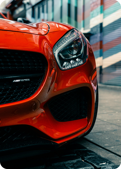 A right close up of a yellow Mercedes AMG sports car headlight on a city street