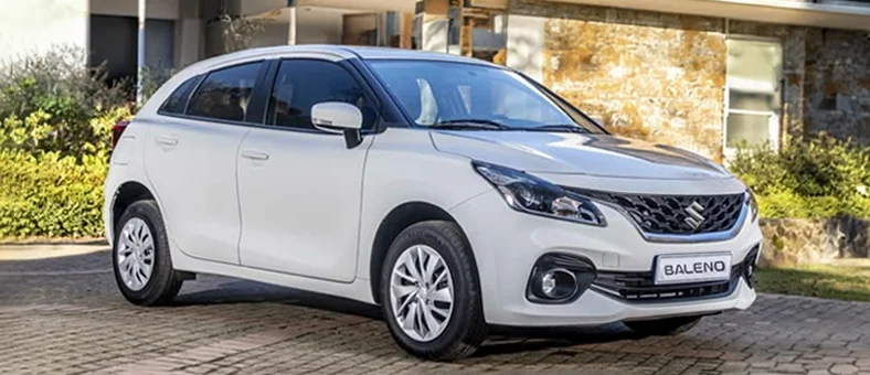 Blue Suzuki Baleno car driving on an urban road, available for rent with Selfdrive, with a red 