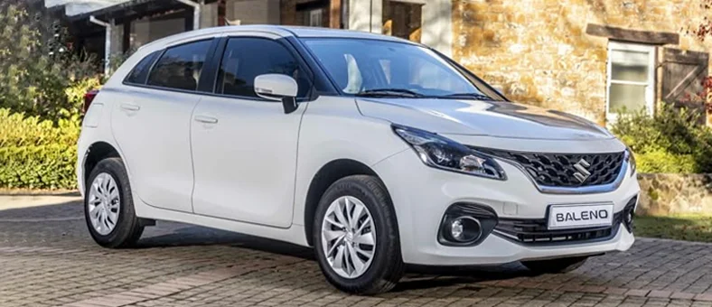 Blue Suzuki Baleno car driving on an urban road, available for rent with Selfdrive, with a red 
